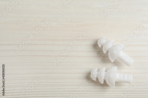 Pair of ear plugs on white wooden background, flat lay. Space for text