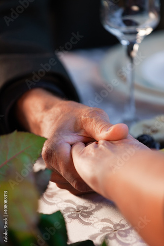 old man and woman hold hands at a romantic dinner at a restaurant