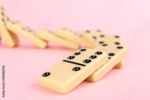 White domino tiles falling on pink background  closeup. Space for text