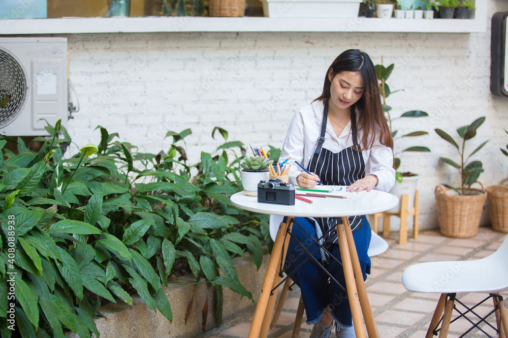 Portrait of Beautiful Asian girl Is opening a small business shop, own coffee shop By planning and working with Tablet with happiness and beautiful smile.