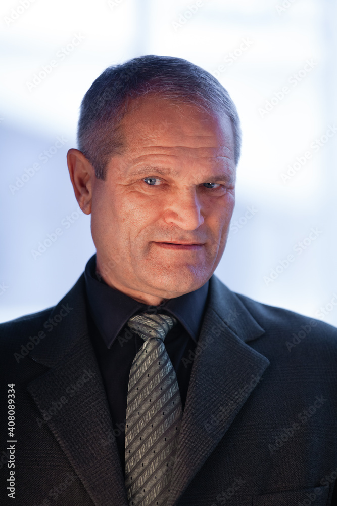Serious elderly man businessman in a suit shrewdly looks into the frame Serious elderly man businessman in a suit shrewdly looks into the frame