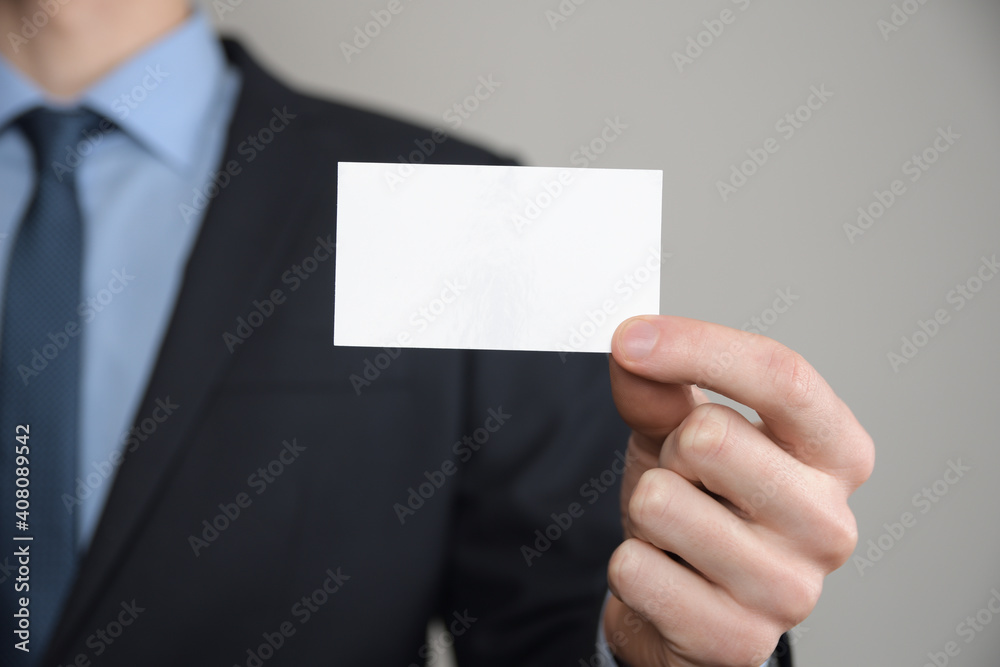 Businessman ,Business Man's hand hold showing business card - close up shot on grey background. Show a blank piece of paper. Paper visit card Businessman ,Business Man's hand hold showing business card - close up shot on grey background. Show a blank piece of paper. Paper visit card