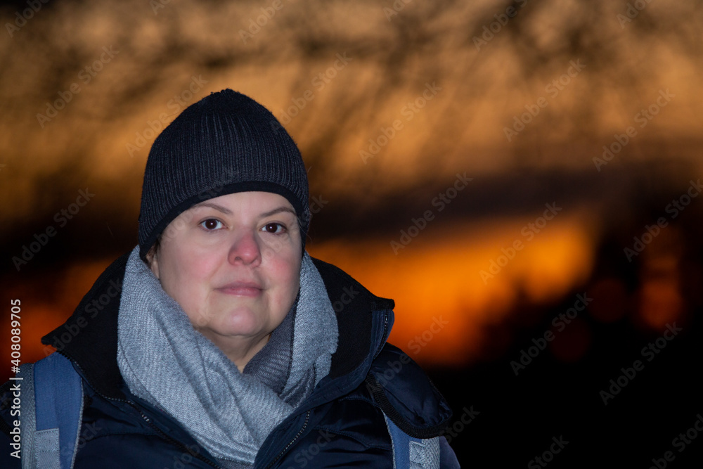 Woman closeup portrait during winter season with the golden hour sky as background Woman closeup portrait during winter season with the golden hour sky as background