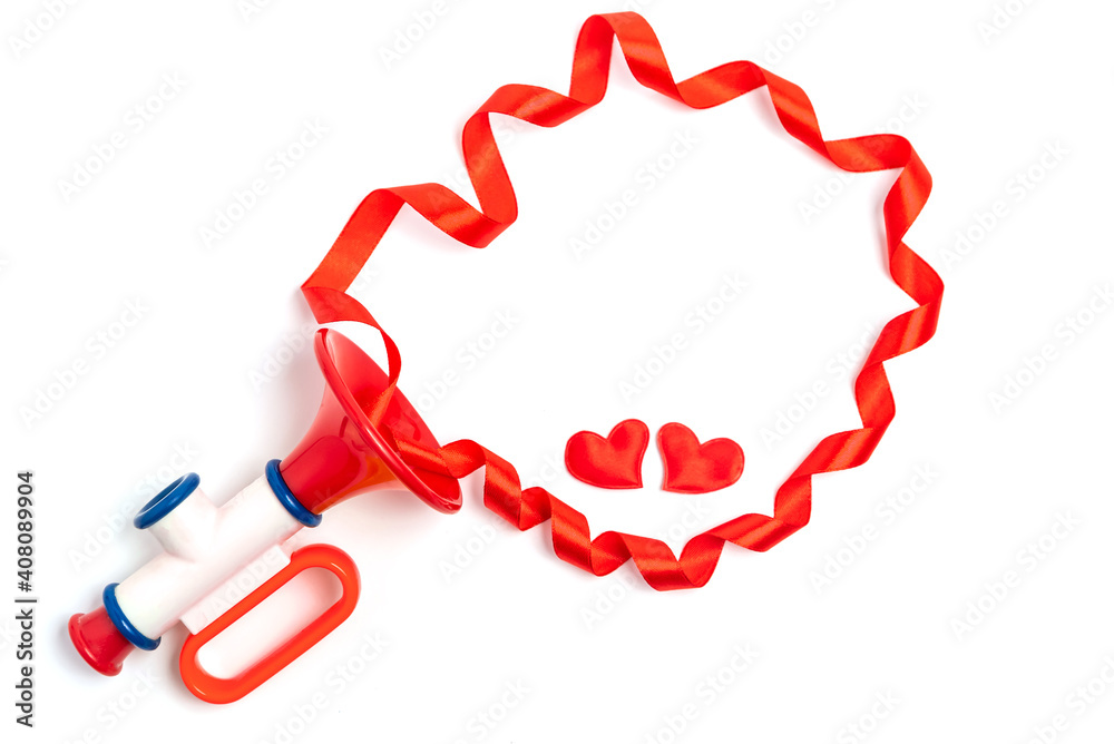 Red hearts and ribbon frame out of the children's toy pipe. The concept of a Valentine's Day love song for sweetheart. Red hearts and ribbon frame out of the children's toy pipe. The concept of a Valentine's Day love song for sweetheart.