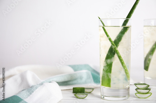 Fresh aloe drink with leaves in glasses on white wooden table. Space for text