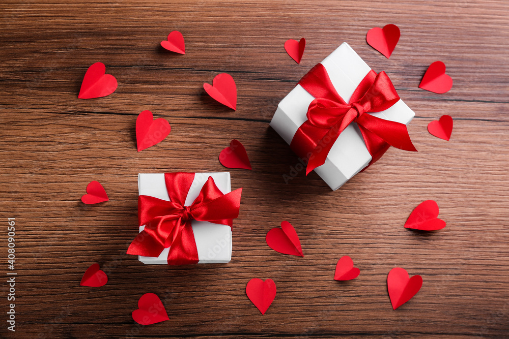 Beautiful gift boxes and paper hearts on wooden table, flat lay. Valentine's Day celebration Beautiful gift boxes and paper hearts on wooden table, flat lay. Valentine's Day celebration