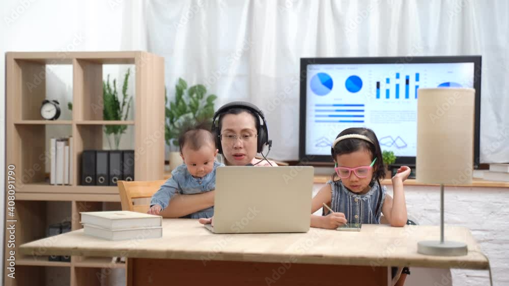 Asian little girl doing homework in living room during her mother working at home Asian little girl doing homework in living room during her mother working at home