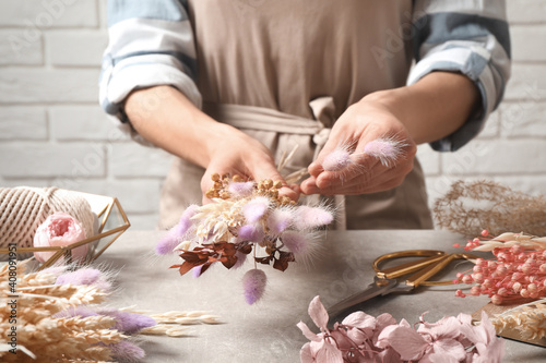 Bloemist die een boeket van gedroogde bloemen maakt aan grijze stenen tafel, close-up