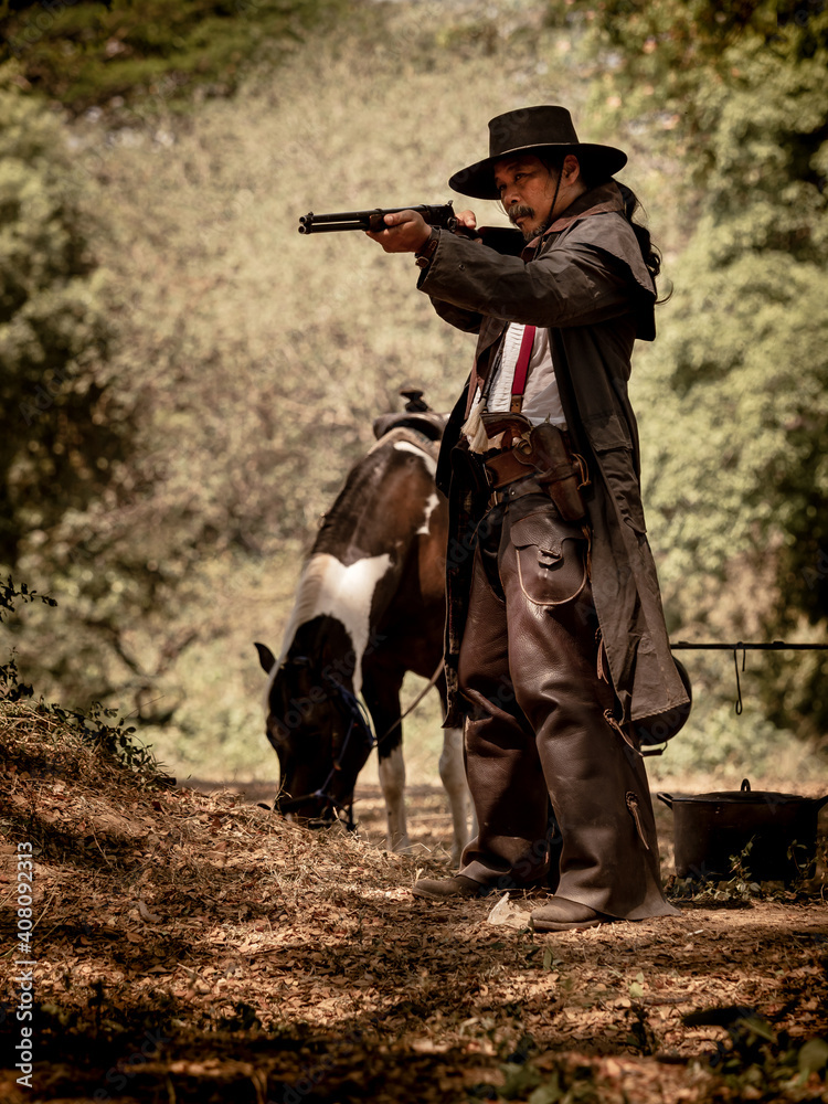 A senior cowboy standing with a gun to guard the safety of the camp in the western area A senior cowboy standing with a gun to guard the safety of the camp in the western area
