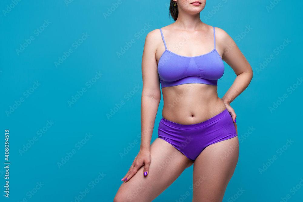 Fototapeta premium Beauty woman in purple underwear with big natural breasts on blue background