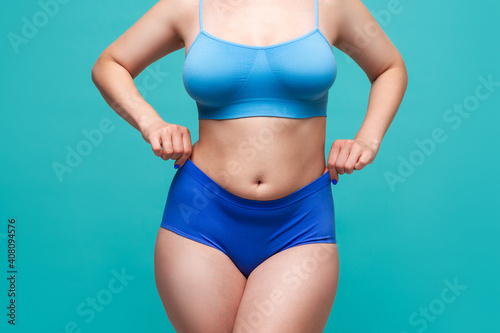 Plus size model in blue underwear on turquoise background © staras