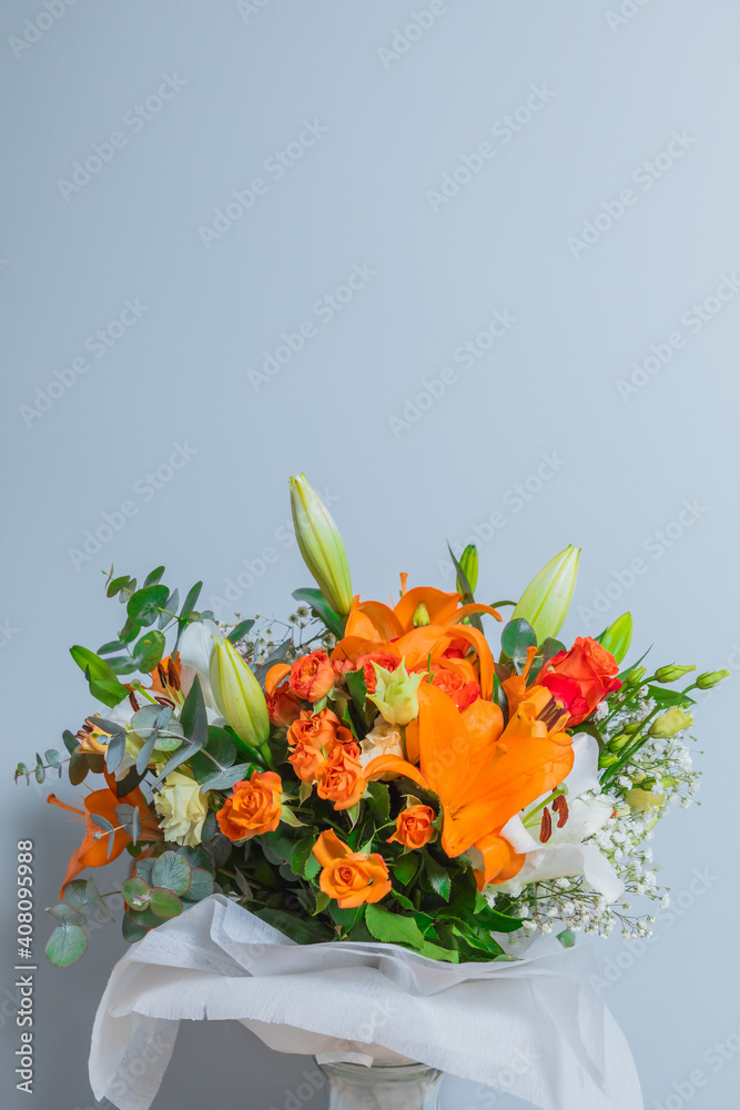 Obraz premium Nice bouquet of flowers on a grey background with space for text. Anniversary, celebration and mother's day gift. Liliums, roses, paniculata and green.