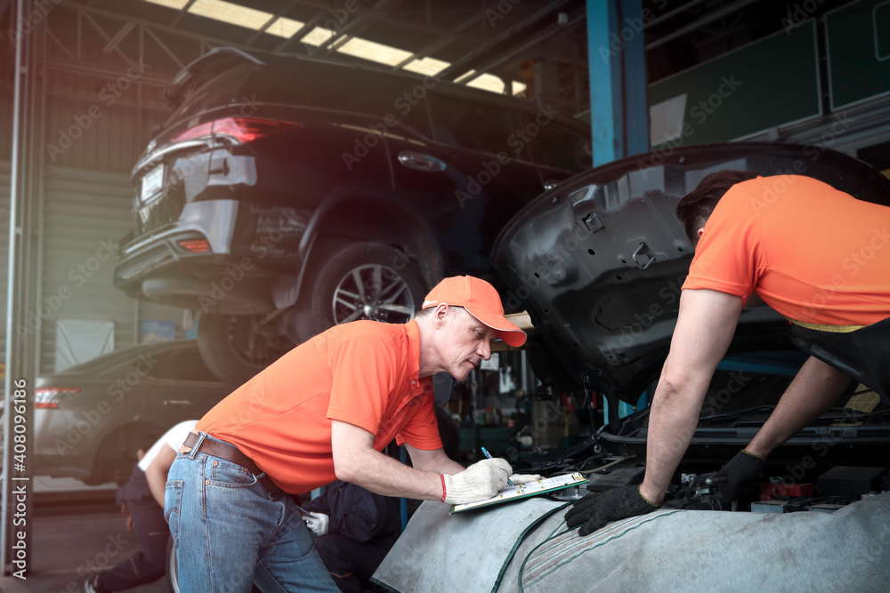 Two mechanic working with engine at garage, car service technician checking and repairing the customer car at automobile service center, vehicle repair service shop concept