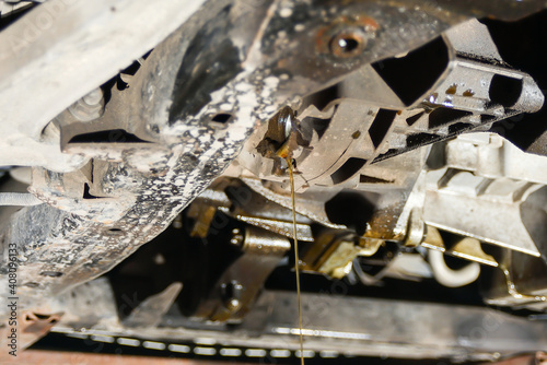 Residual engine oil on a car is drained from the engine sump at an auto repair shop.