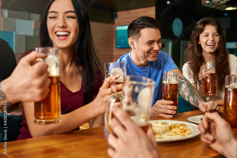Company laughing and joking while drinking tasty beer in pub
