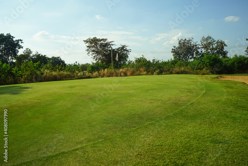 Background of evening golf course has sunlight shining down at golf course in Thailand. Nice scenery on a golf course at a late summer afternoon. © somchai
