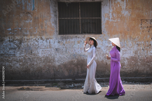 Young Vietnam woman wearing Ao Dai culture traditional walking on local street at Ho Chi Minh in Vietnam,vintage style,travel and relaxing concept.