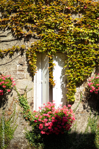 White wooden shutters in a stone house decorated with flowers.