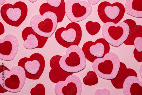 Full frame of red and pink felt hearts on light pink background