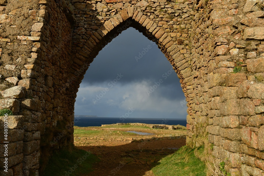 Gronez Castle ruin, Jersey, U.K. 13th century medieval stone arch framing the cliff coast to the other Channel Islands with a moody Winter sky.