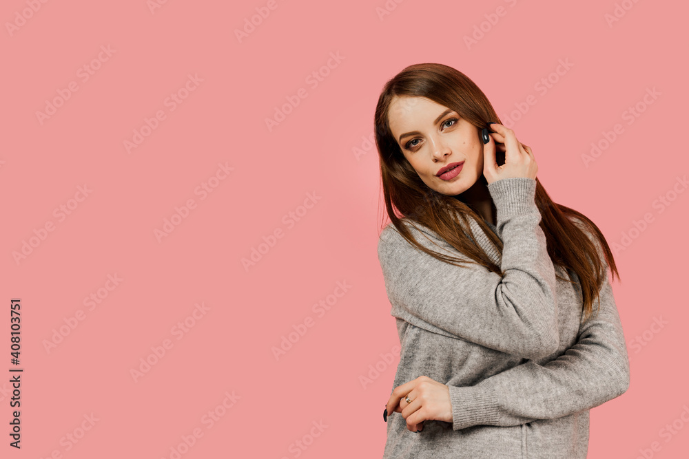 Professional model posing in studio. Lifestyle of caucasian happy girl. Beauty portrait of a woman weared grey sweater on pink background.