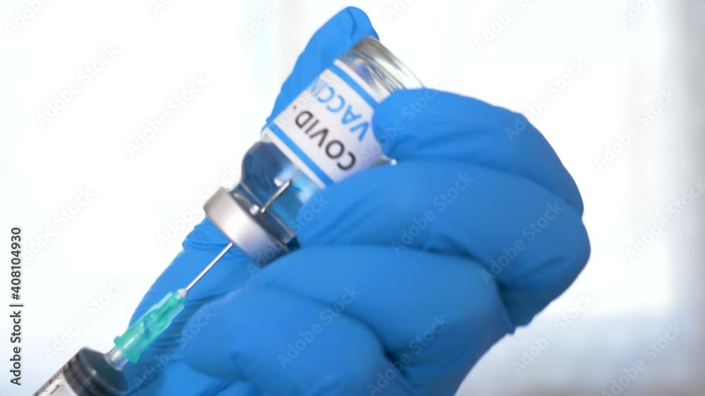 Doctor hands with blue surgical gloves holding syringe and COVID-19 vaccine. COVID-19 vaccine concept. Health and medical concept. Selective focus, Close up syringe and vaccine dose. Macro 4K video. Doctor hands with blue surgical gloves holding syringe and COVID-19 vaccine. COVID-19 vaccine concept. Health and medical concept. Selective focus, Close up syringe and vaccine dose. Macro 4K video.