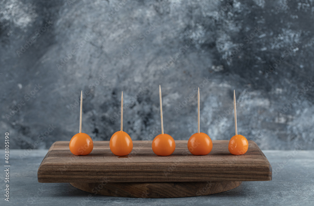 Orange tomatoes with sticks on wooden board Orange tomatoes with sticks on wooden board