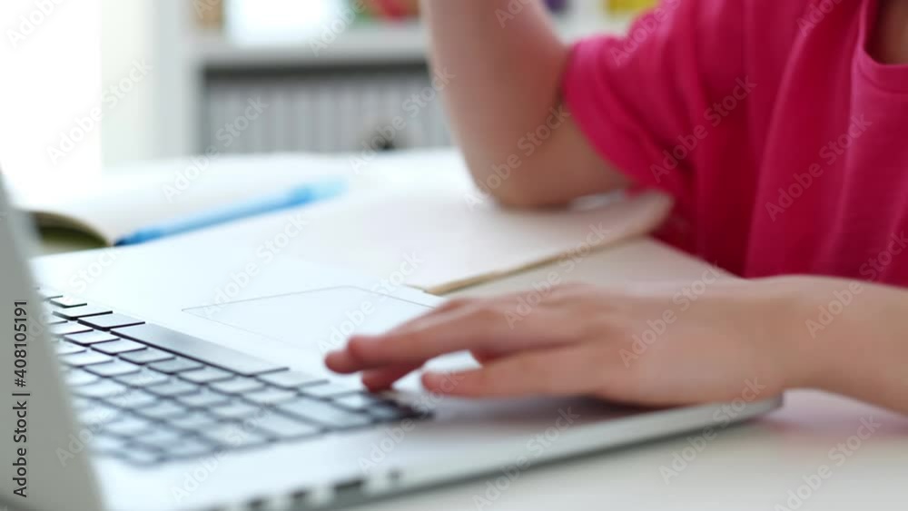 Little girl using fingers on laptop touchpad while typing on keyboard Little girl using fingers on laptop touchpad while typing on keyboard