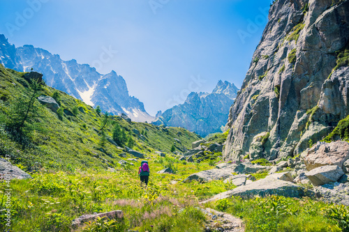 Hiker walking up to the Fenetre d'Aprette through a valley along  rock stone wall, Tour du Mont Blanc, Switzerland