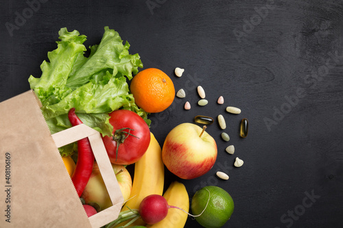 Paper bag with natural vegetables and fruits on a dark background with a copy space side view. The concept of healthy vegetarian food. Online delivery.