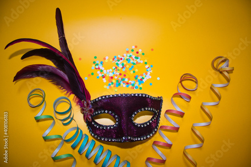 Fotografija purple carnival mask with confetti on a yellow background