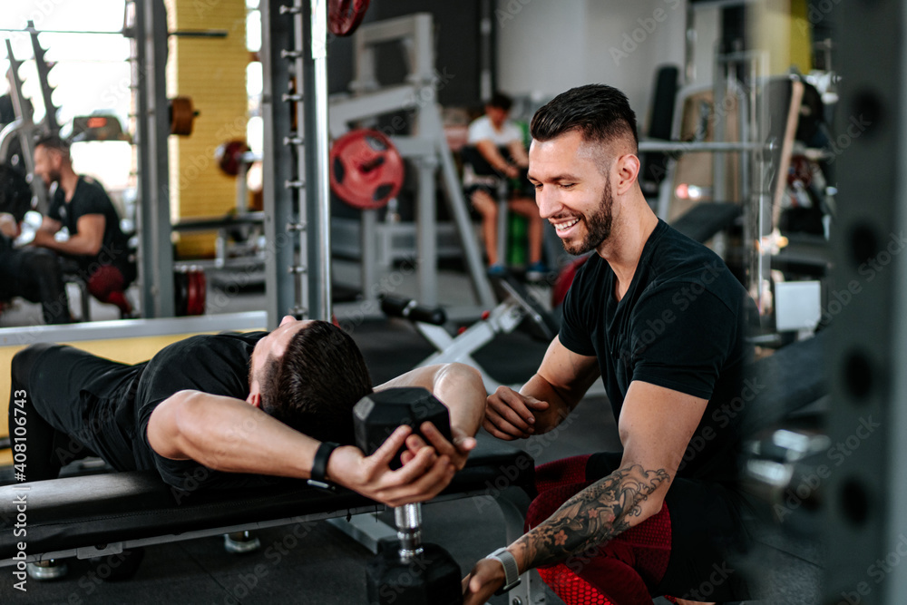 Smiling man, Personal trainer helping, assisting client in the gym and doing workout. Healthy lifestyle fitness session with personal trainer.. Smiling man, Personal trainer helping, assisting client in the gym and doing workout. Healthy lifestyle fitness session with personal trainer..