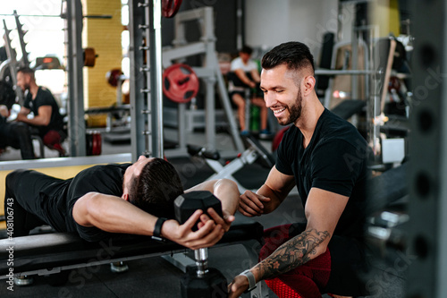 Smiling man, Personal trainer helping, assisting client in the gym and doing workout. Healthy lifestyle fitness session with personal trainer..