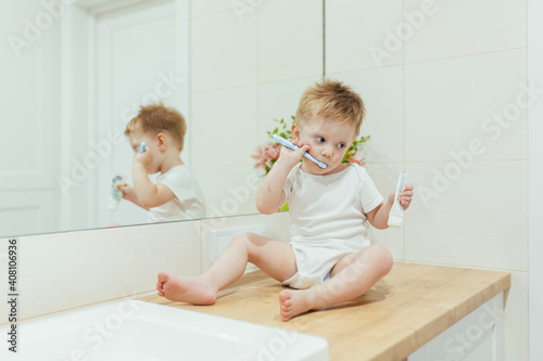 Little kid boy brushing teeth in his bathroom, baby taking care of teeth