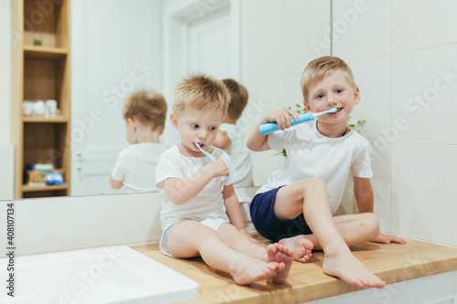 Little boys kids brush their teeth in their bathroom, two little brothers learn hygiene and dental care