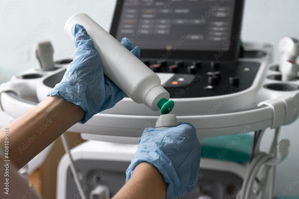 Close up of female's hands operating ultrasound machine. The doctor prepares to do an ultrasound examination