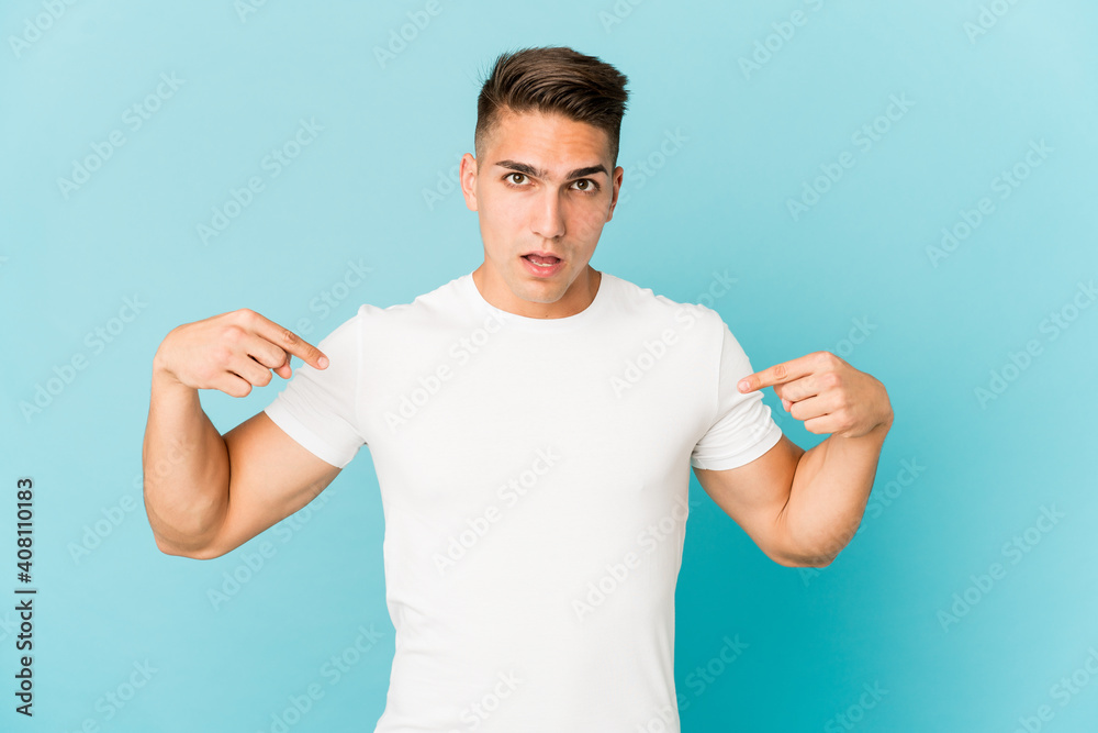 Young caucasian handsome man isolated points down with fingers, positive feeling.