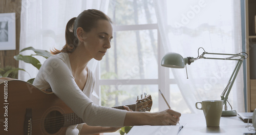 Woman playing guitar at home and composing music