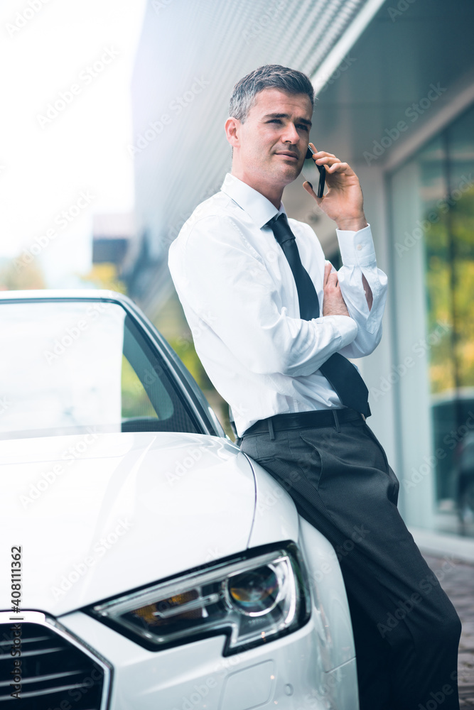 Confident manager leaning on his car Confident manager leaning on his car