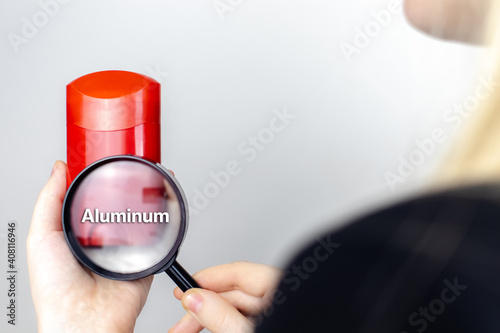 A woman examines the harmful ingredients of the antiperspirant a magnifying glass. Dry stick deodorant stick with Aluminum. The concept of hazardous substances in cosmetics and household chemicals photo