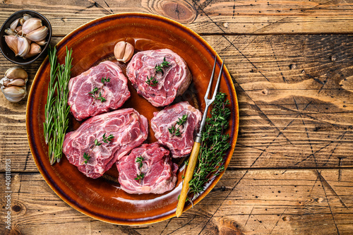 Mutton lamb neck meat on a rustic plate with thyme and rosemary. wooden background. Top view. Copy space