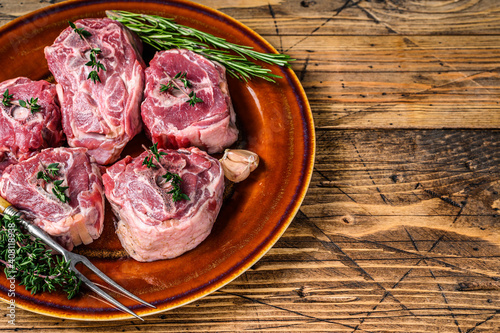 Mutton lamb neck meat on a rustic plate with thyme and rosemary. wooden background. Top view. Copy space