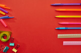 Pens, rulers and paper clips, red background