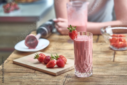 Strawberry smoothie on wooden table in the kitchen. Healthy eating, cooking and summer refreshment concepts.