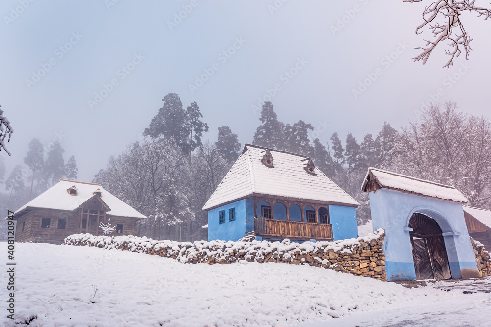 Traditional Romanian village in Transylvania with old house straw roofing covered with snow in a cold day