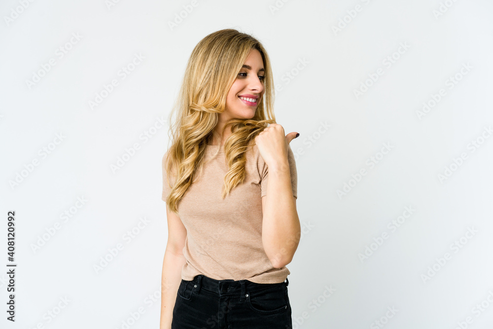 Young caucasian blonde woman points with thumb finger away, laughing and carefree. Young caucasian blonde woman points with thumb finger away, laughing and carefree.