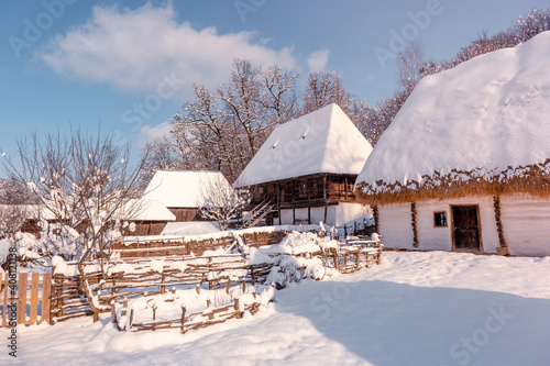 Traditional Romanian village in Transylvania with old house straw roofing covered with snow in a cold day © Roberto Sorin