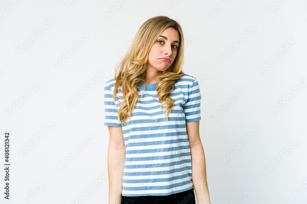Young caucasian blonde woman shrugs shoulders and open eyes confused.
