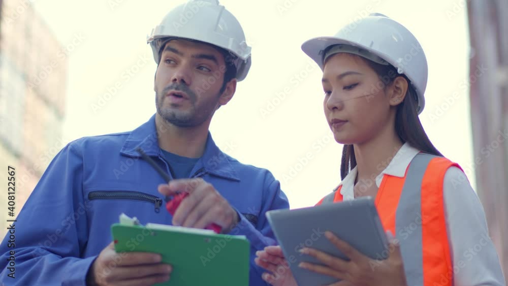 Two engineer male and female worker dockers in checking examine discussion, in front of a large industrial harbor,Engineer or foreman or worker checking and talking together shipyard Job concept Two engineer male and female worker dockers in checking examine discussion, in front of a large industrial harbor,Engineer or foreman or worker checking and talking together shipyard Job concept