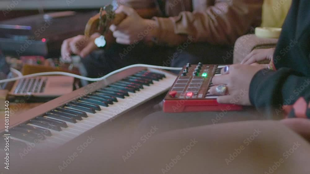 Two musicians making music together on a mini keyboard and a bass guitar